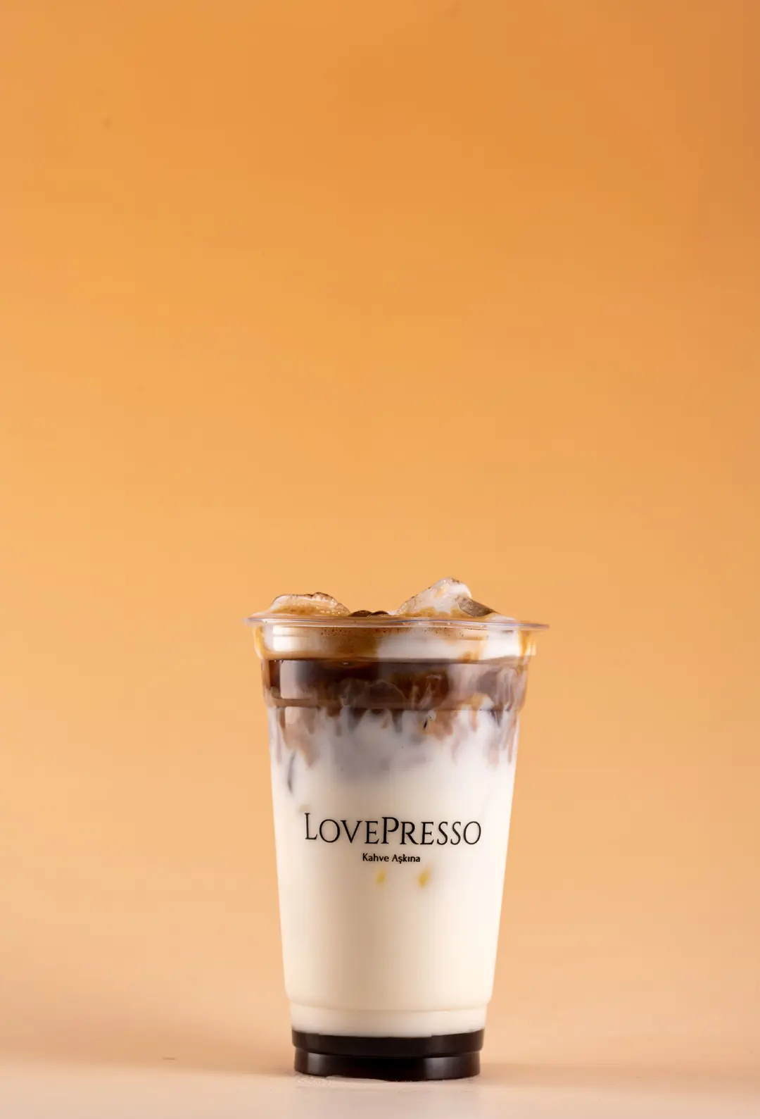 LovePresso iced latte açık kap buz mermer efekti, turuncu amber gradient fon — İzmir cafe ürün fotoğrafı, Mert Akdurak