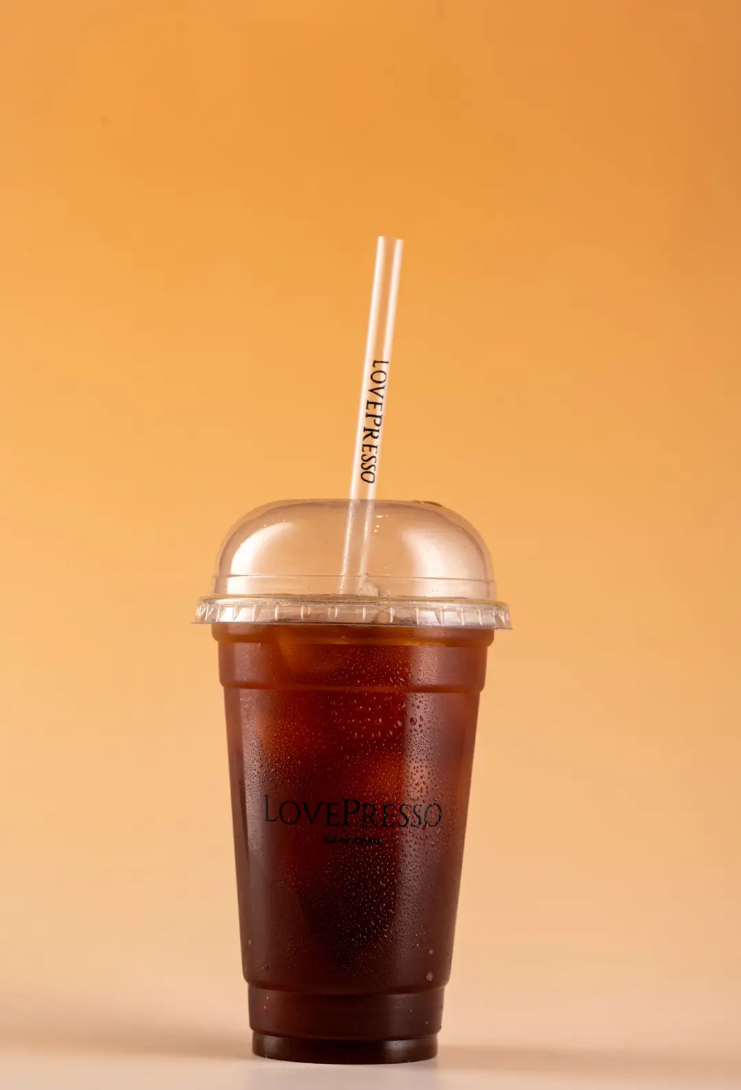 LovePresso iced americano soğuk kahve dome kapak, turuncu amber gradient PVC fon — İzmir franchise kahve fotoğrafı, Mert Akdurak