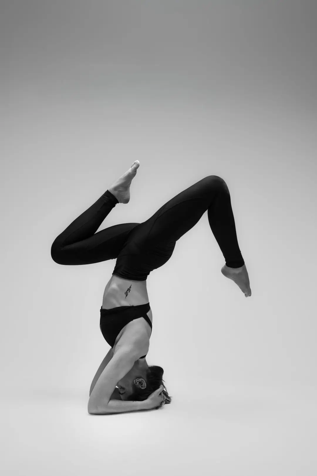 İzmir stüdyosunda yoga eğitmeni Melis'in (@yogawithmelis) gri fon önünde siyah beyaz asana pozuyla sergilediği estetik ve güçlü yoga duruşu.