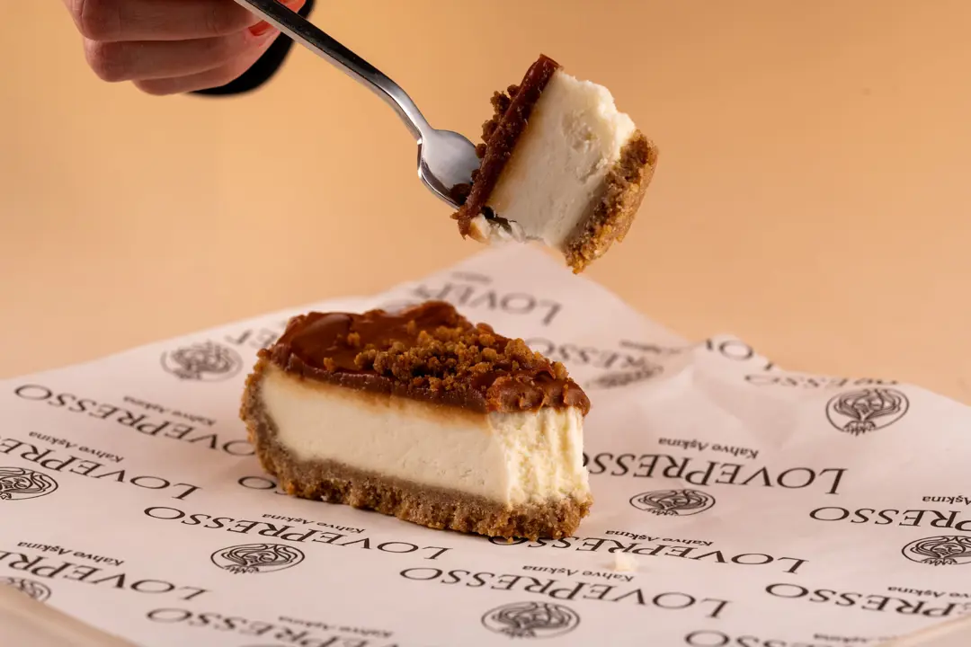 LovePresso karamel cheesecake kaşık el lifestyle yeme anı, turuncu amber gradient fon — İzmir franchise menü fotoğrafçısı, Mert Akdurak