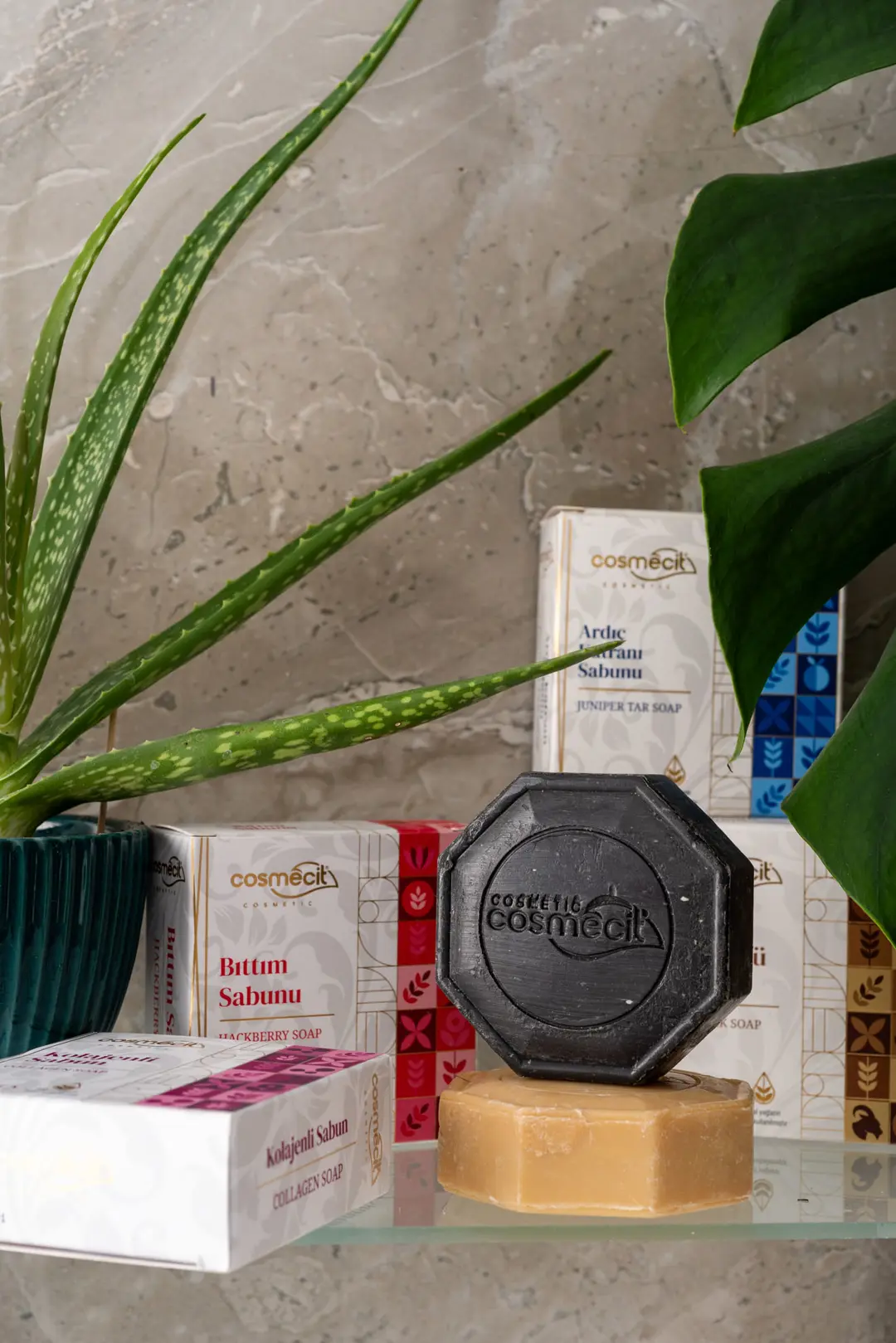 İzmir mecitefendi konseptiyle hazırlanan mermer rafta, aloe vera yaprakları arasında estetik sekizgen doğal sabunlar sergileniyor.