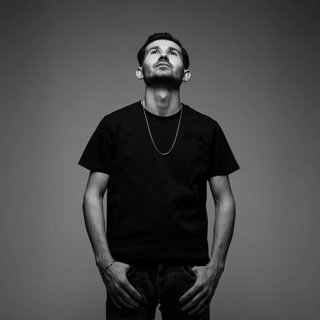 Yasin Göncü tam boy portre fotoğrafı, yukarı bakış, siyah tişört, eller cepte — İzmir spotify albüm kapağı fotoğrafı