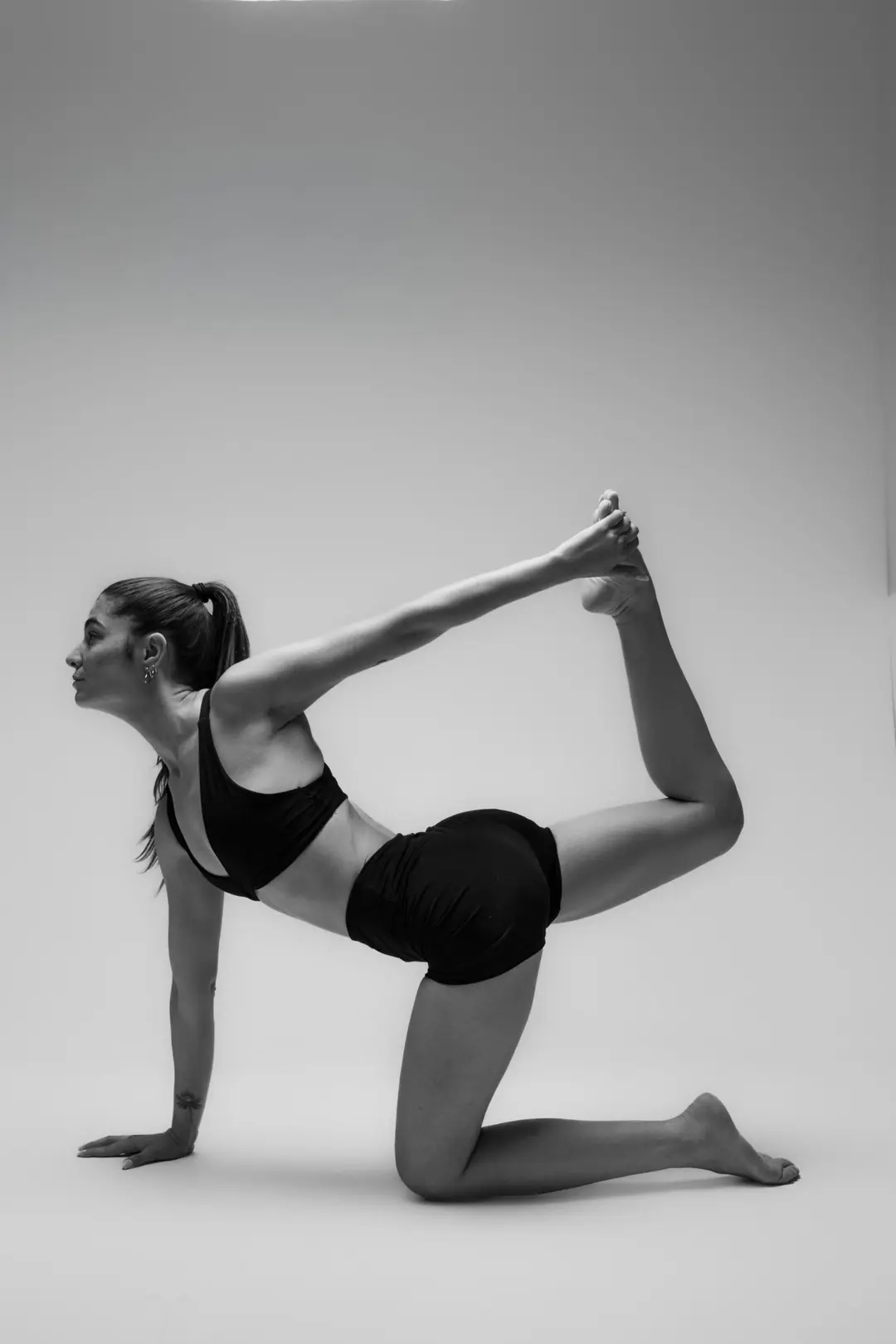 İzmir'deki stüdyoda gri fon önünde siyah beyaz asana duruşu yapan yogawithmelis, estetik ve güçlü bir yoga pozu sergiliyor.