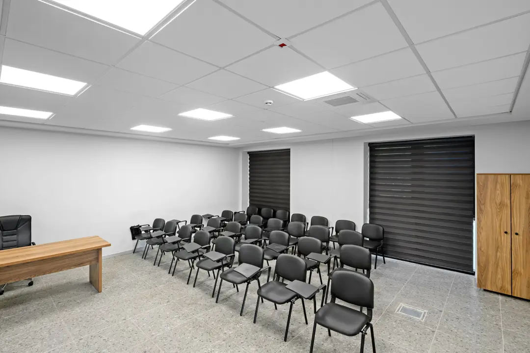 Geniş açıyla itfaiye eğitim salonu: 60x60 asma tavan, LED panel dizisi, eğitmen masası ve ahşap dolap.