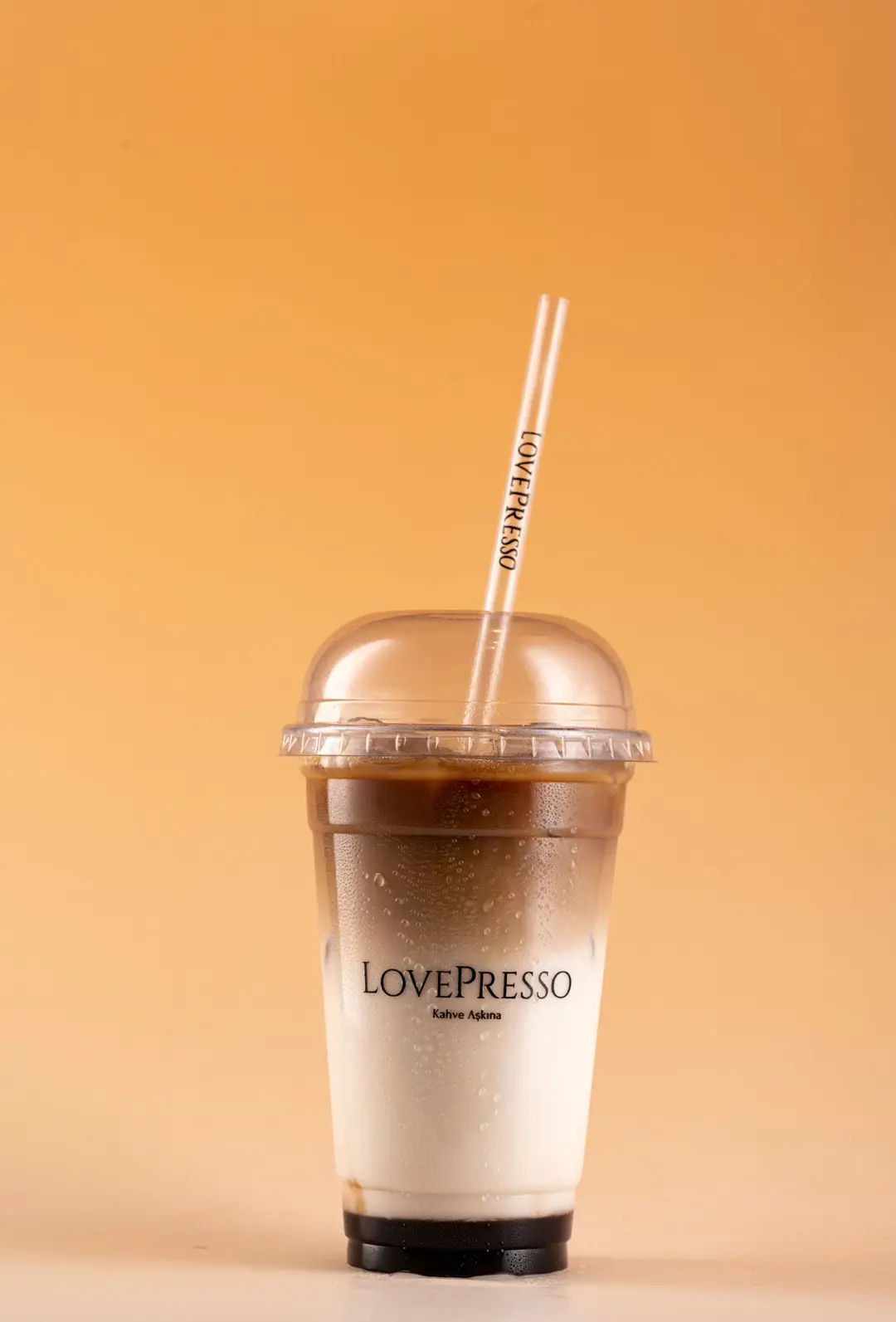 LovePresso iced latte dikey format yoğunlaşma efekti, turuncu amber gradient PVC fon — İzmir website içecek fotoğrafı, Mert Akdurak