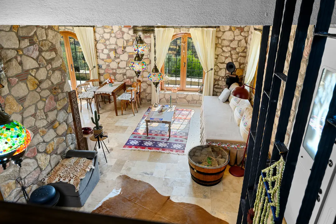 İzmir Torbalı taş ev salonunda, doğal taş duvarlar ve renkli mozaik lambalar flambient çekimle sıcak ve otantik bir atmosfer yaratıyor.