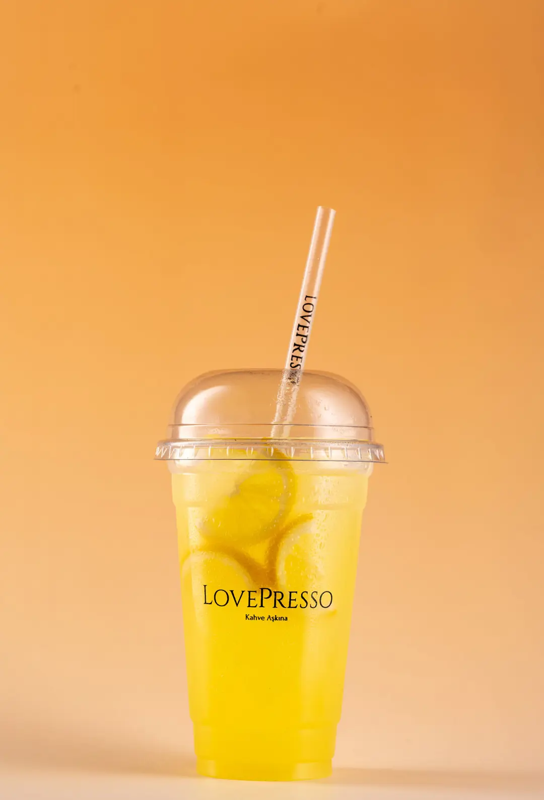 LovePresso limonata limon dilimleri buz, turuncu amber gradient PVC fon — İzmir takeaway içecek fotoğrafçısı, Mert Akdurak